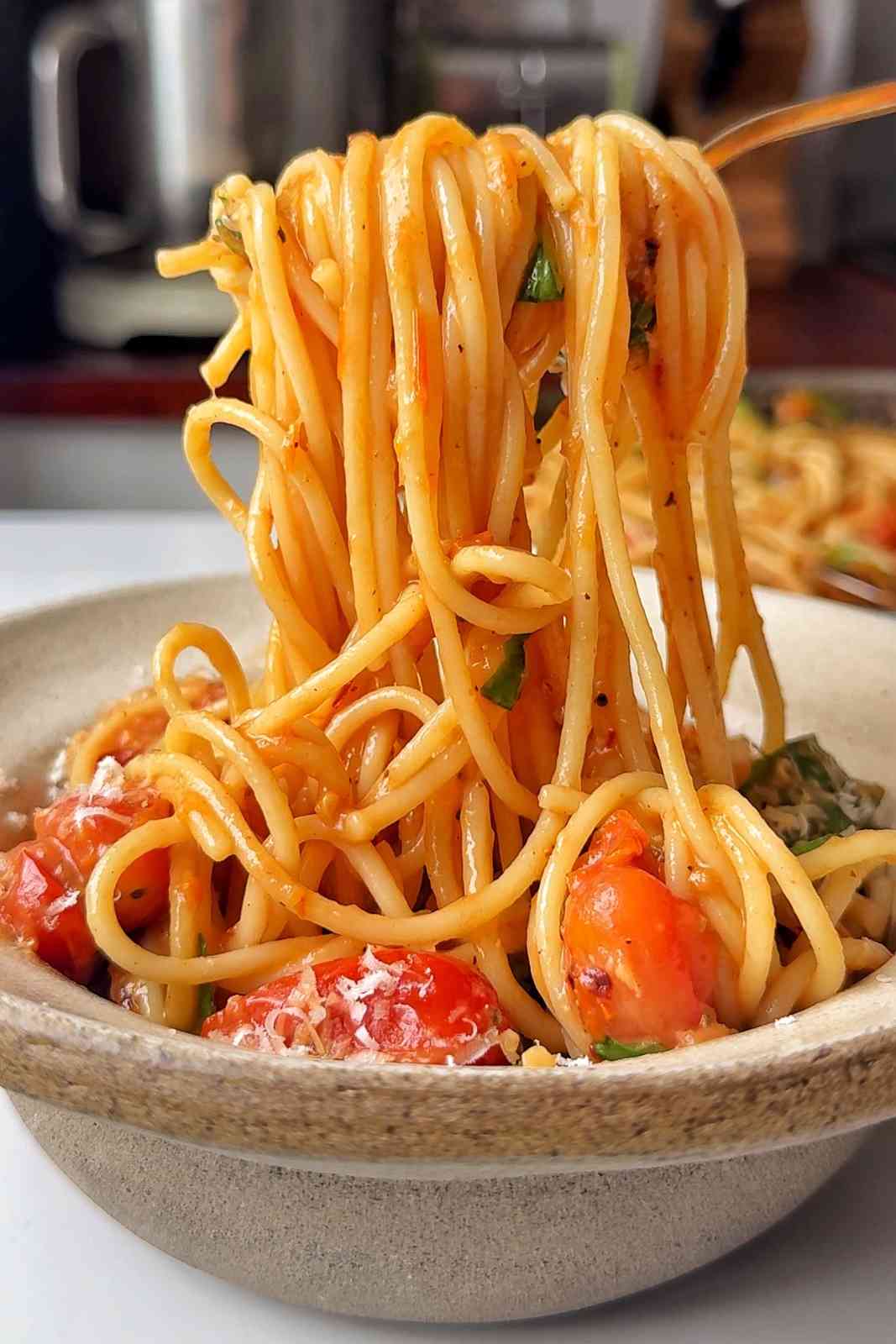 spaghetti being lifted up with a fork in a white bowl.