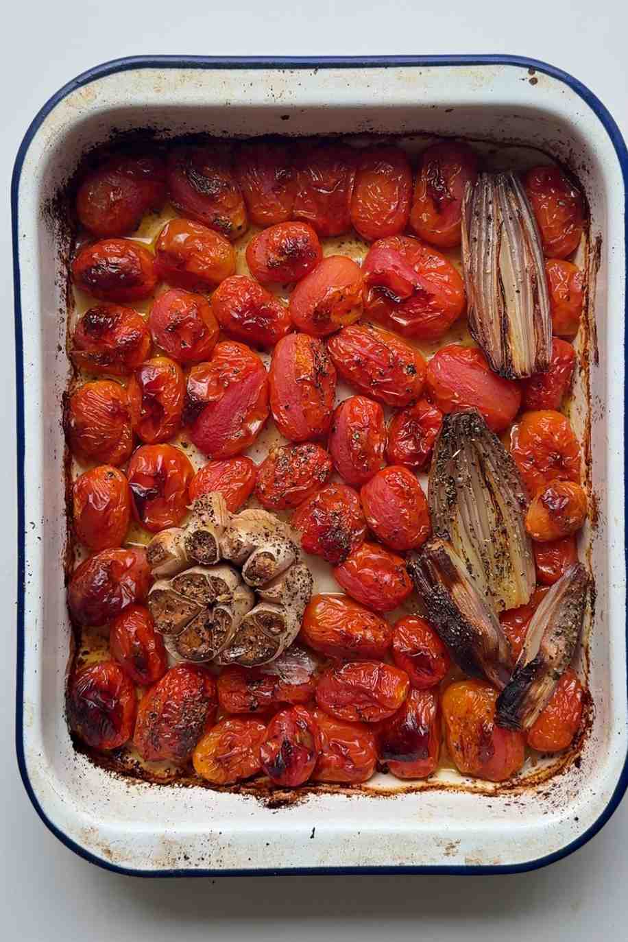 Roasted baby tomatoes in a tin with shallots and garlic.