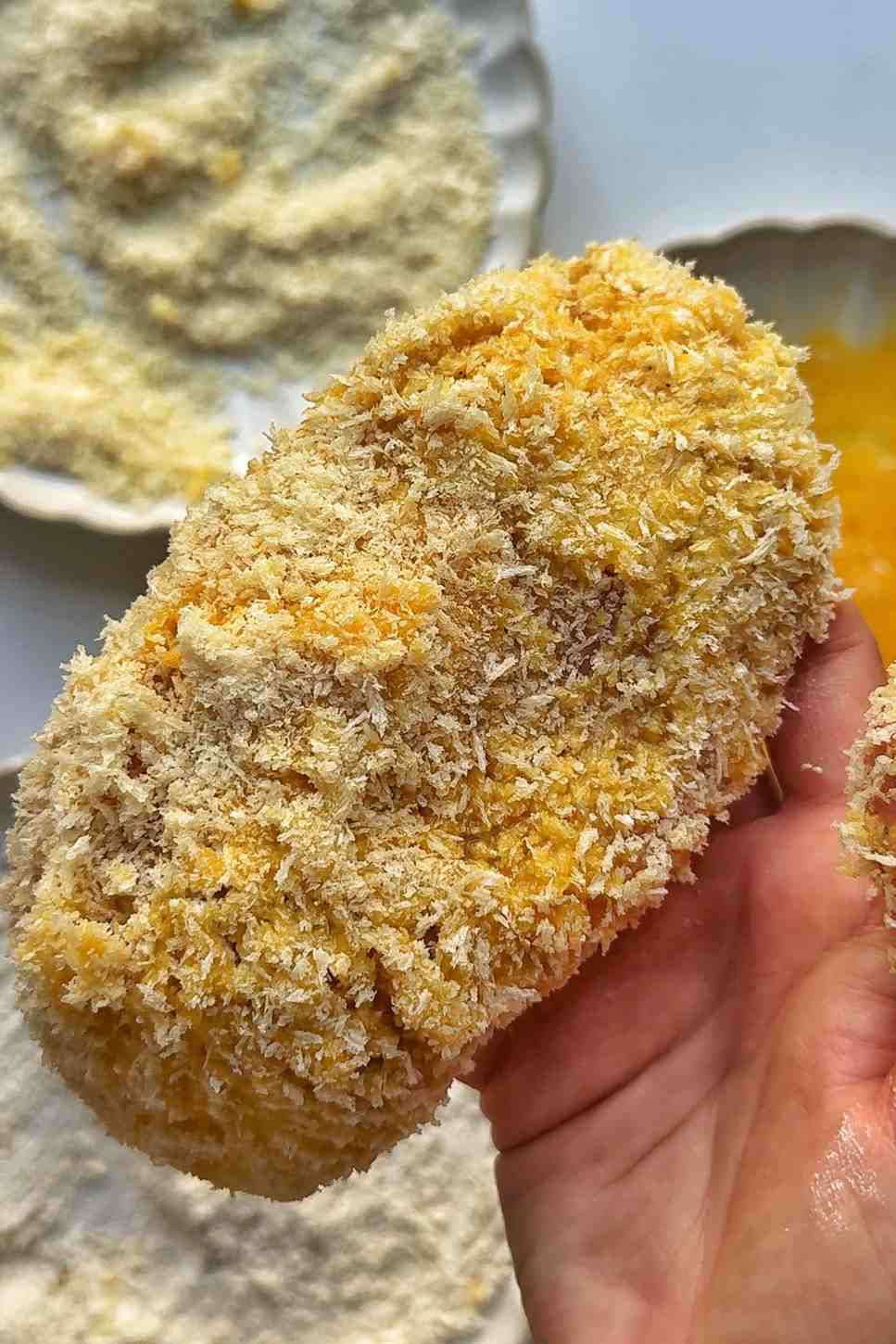 Coating chicken breast in panko breadcrumbs.