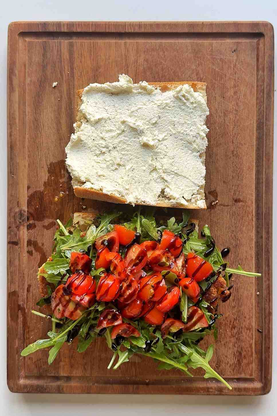 Assembling the summer sandwich on a wooden chopping board.