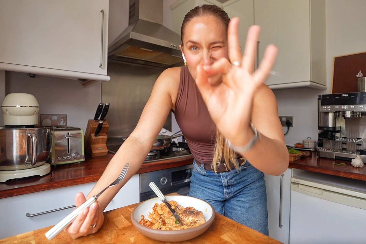Emily holding a fork over a bowl of marry me chicken and rice in her kitchen.
