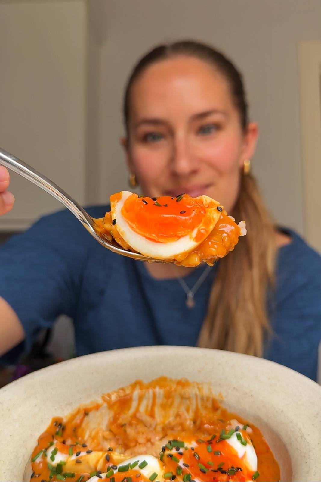 Showing jammy egg up to the camera with Emily Roz in the background smiling.