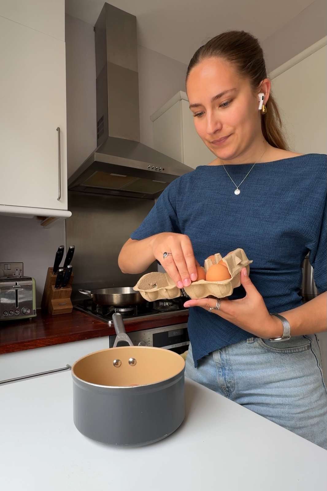 Emily placing eggs into a pan of boiling water.