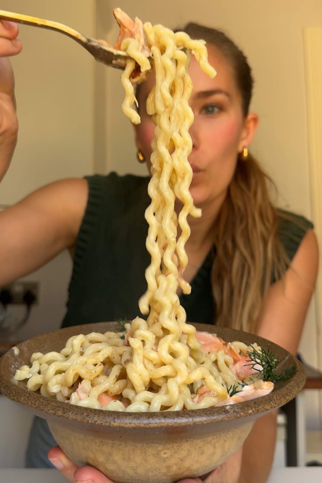 Emily Roz pulling salmon pasta using a fork.