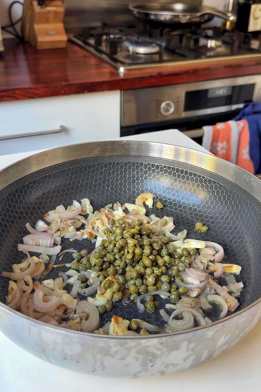 Frying shallots, garlic, and capers in a pan.
