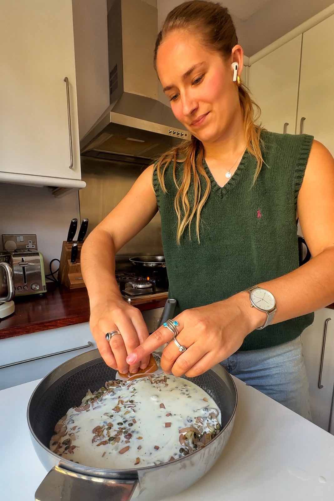 Pouring cream into the pasta sauce.