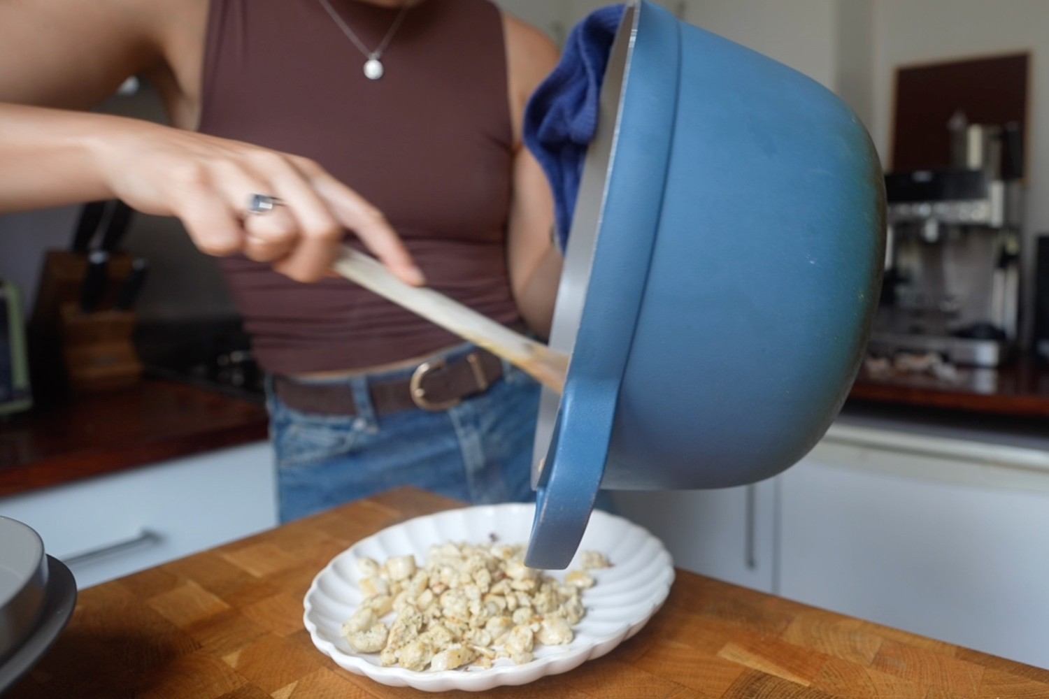 Emily tipping browned crumbled sausage meat out of a blue pot onto a white scalloped plate.