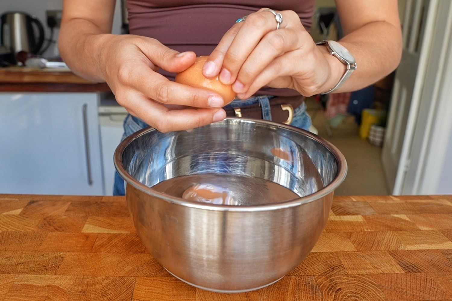 Emily peeling a soft-boiled egg in a bowl of cold water.