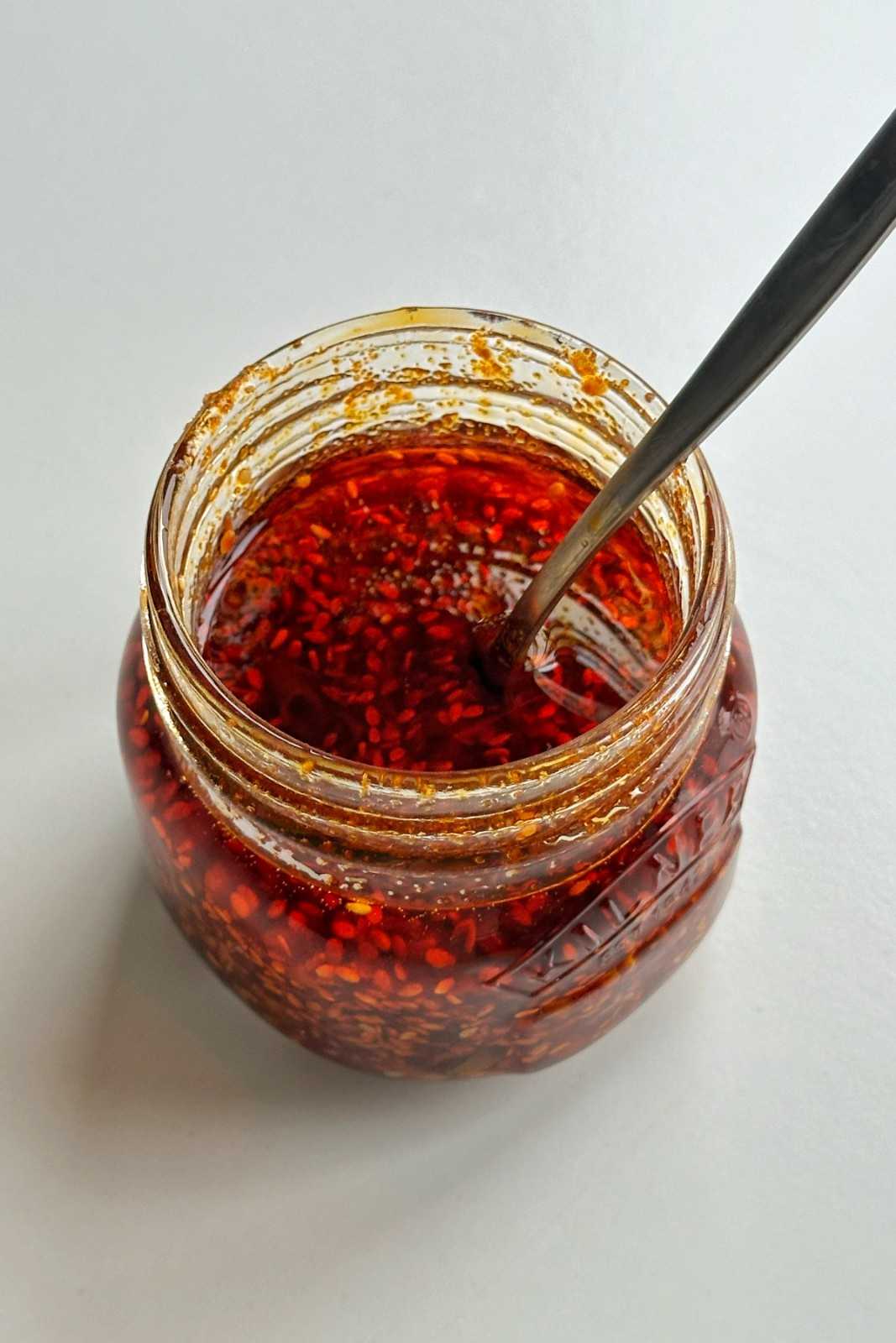 A jar of homemade Vietnamese-inspired chili oil with chili flakes and sesame seeds, similar in texture to salsa macha.