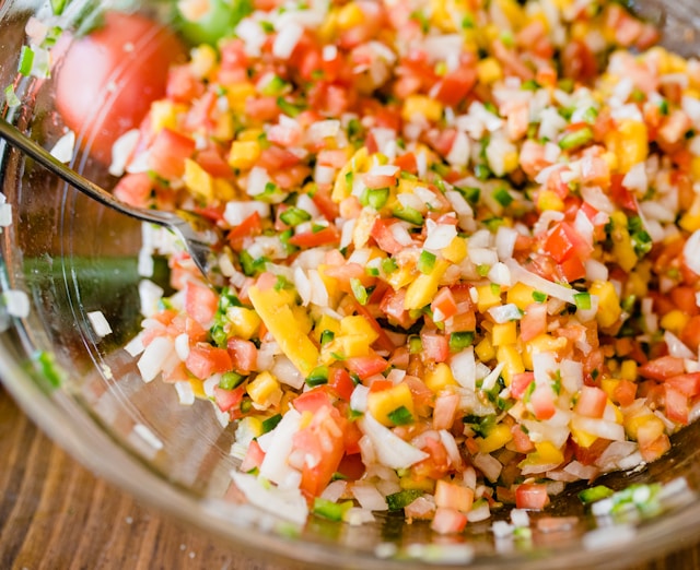 Close-up of fresh pico de gallo in a glass bowl with finely diced tomato, white onion, yellow pepper and jalapeño.