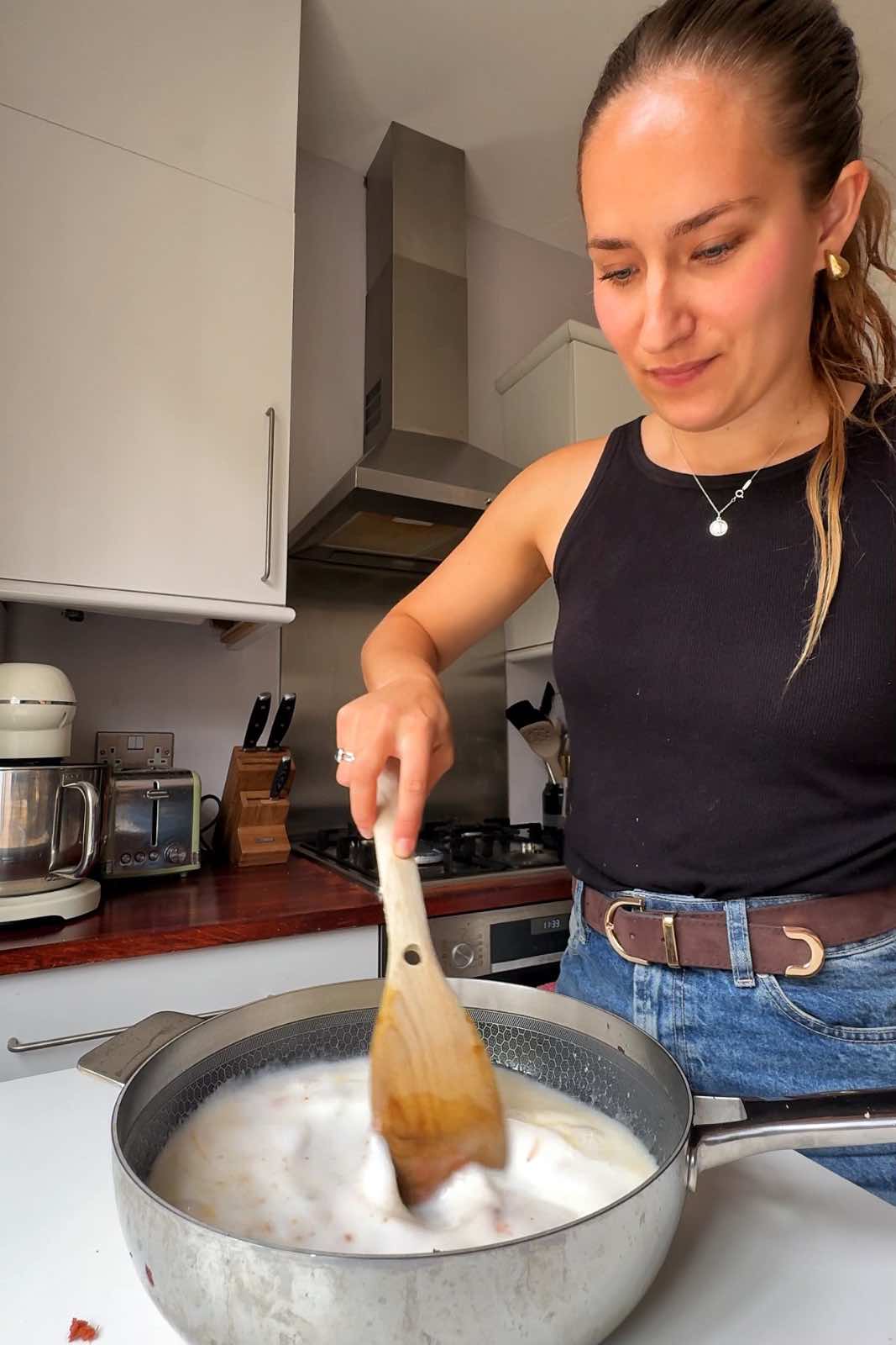 Emily Roz stirring a pan of coconut Thai milk.