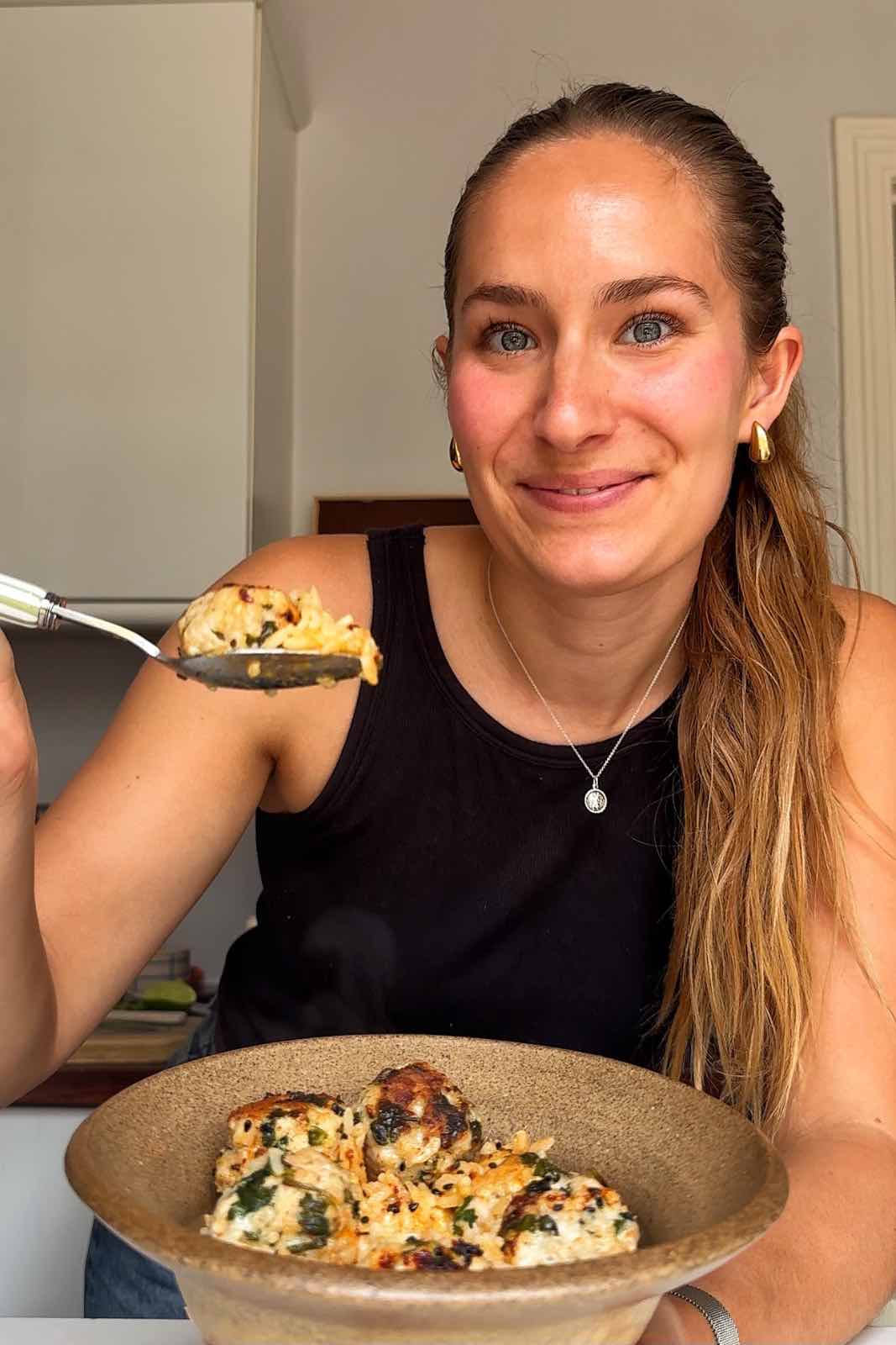 Emily Roz holding up a spoon of Thai chicken meatballs.