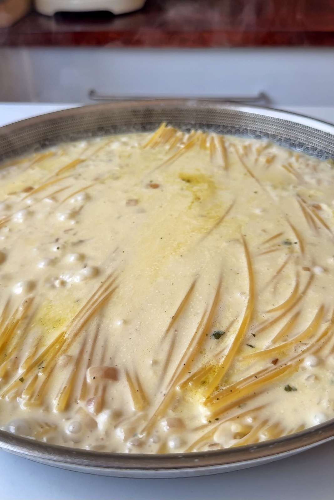 Adding spaghetti into the creamy mixture to cook.