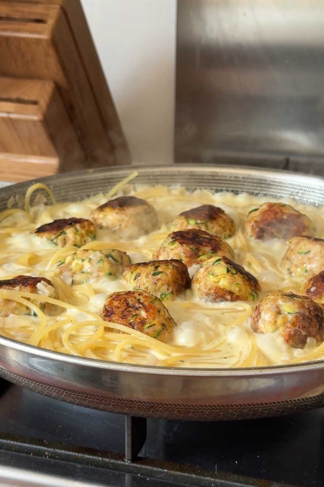 Cooking the meatballs in the pasta sauce.