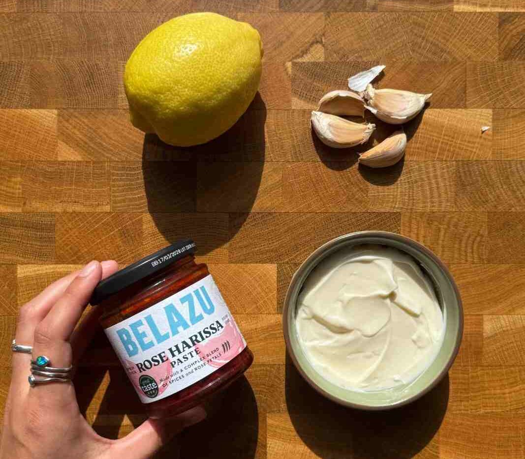 Aioli, lemon, garlic and harissa paste on a wooden chopping board ready to be made into a bruschetta dip.