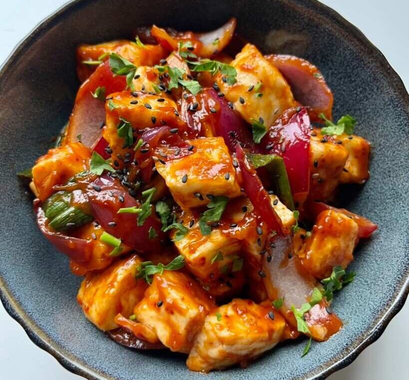 A bowl of cubes of cornstarch-coated halloumi fried until golden, tossed in a sauce of soy, sriracha, ketchup and gochugaru.
