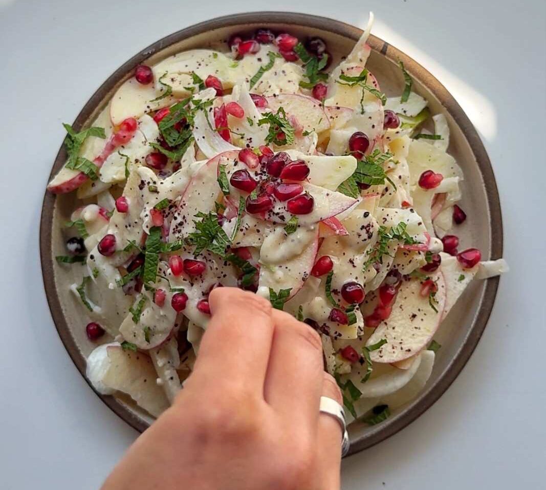 Em spreading pomegranate seeds on top of her apple fennel salad.