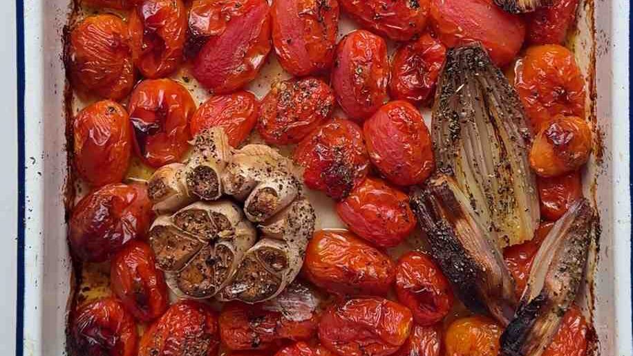 Roasting tin full of roasted tomato and garlic. 