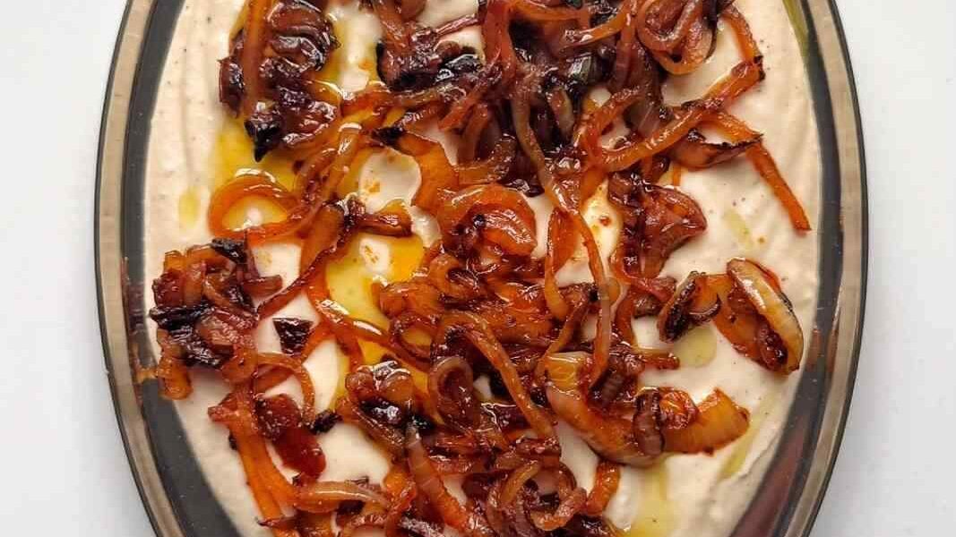 White Bean Bruschetta Dip topped with caramelised onions on a silver platter.