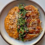 Crispy romesco chicken over jasmine rice in a stoneware bowl, with romesco sauce, a cilantro and chili green sauce and grated parmesan.