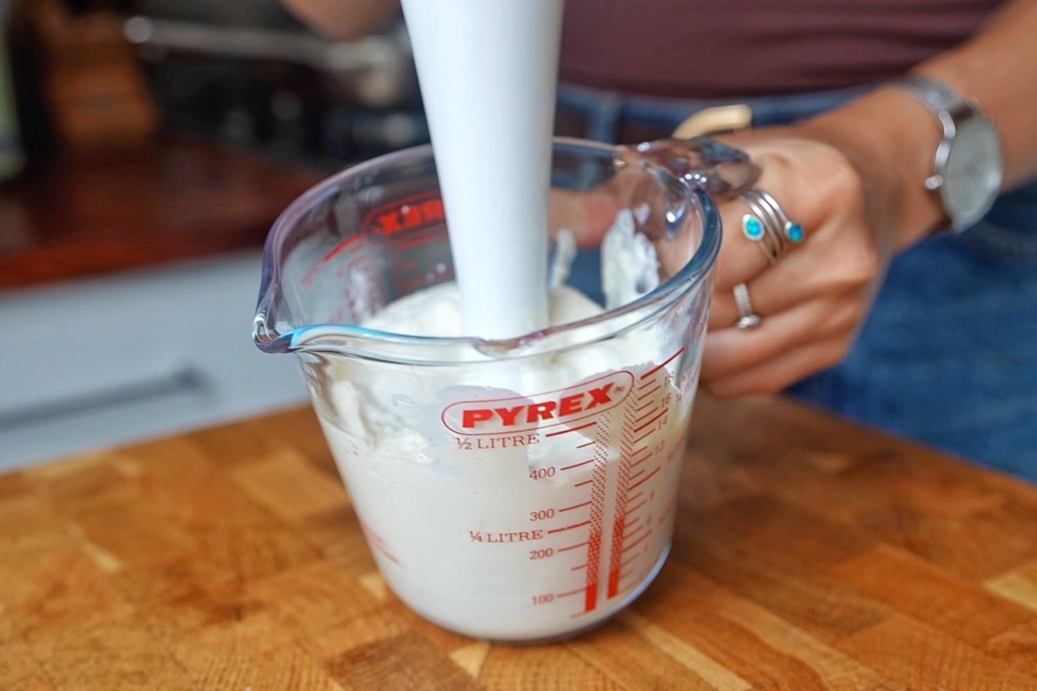 Blending silken tofu with a hand blender in a glass measuring jug.