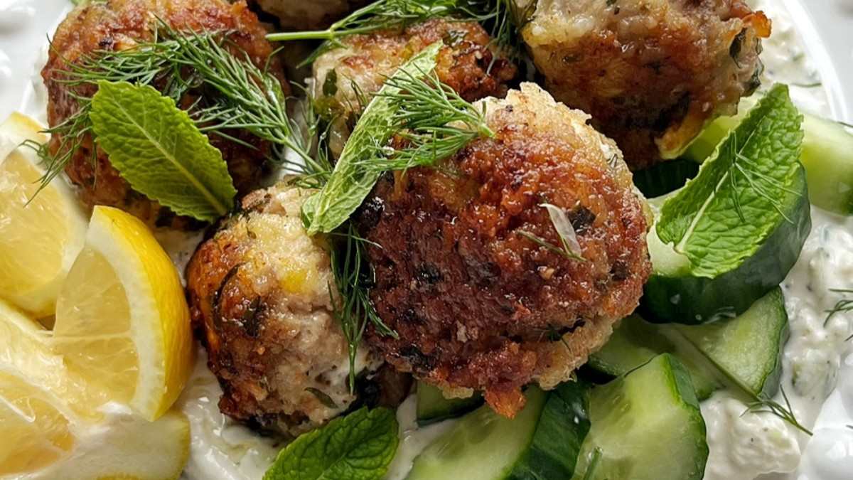 Plate of Greek meatballs (keftedes) on feta tzatziki with lemon, dill and mint.