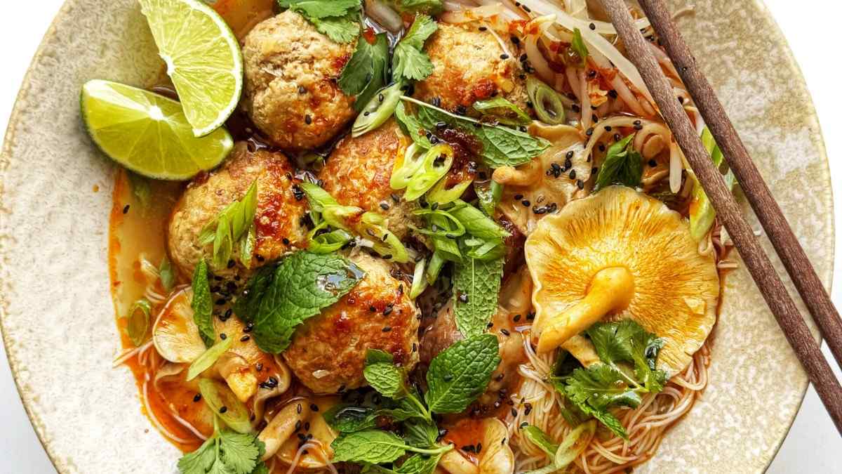 Thai-style pork meatball noodle soup in a bowl with chopsticks on the side.