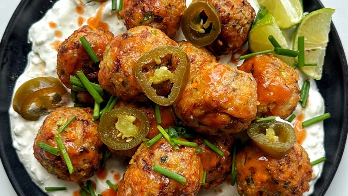 Plate of air fryer chicken meatballs in buffalo sauce with homemade blue cheese sauce.