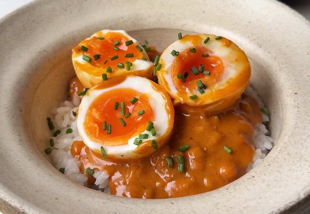 Garnishing the peanut gochujang chili eggs with chives and sesame seeds.
