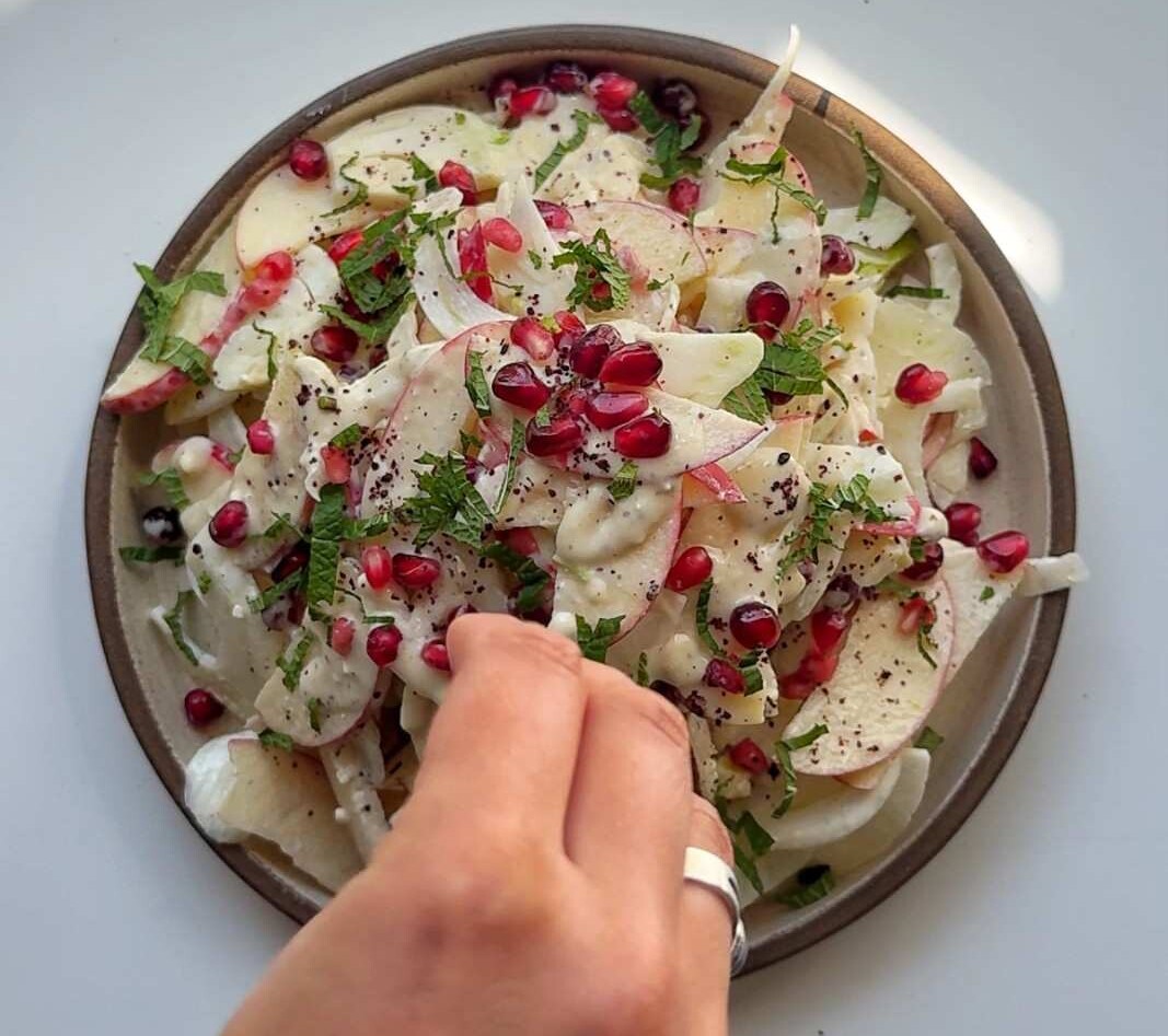 Garnishing the fennel apple salad with mint and pomegranate.
