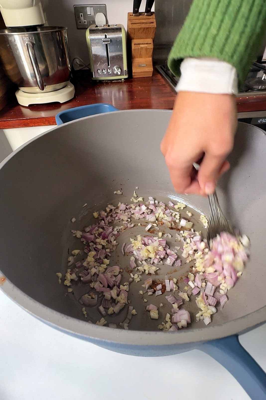 Finely diced shallots and minced garlic being stirred in olive oil in the pan used to sear the chicken.