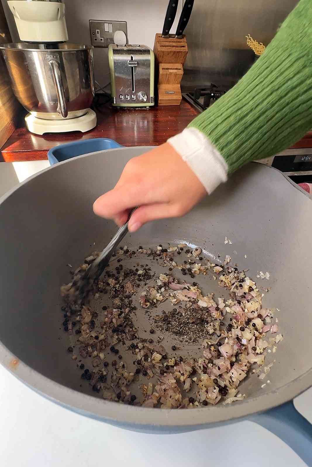 Whole black peppercorns and freshly ground black pepper frying with softened shallots and garlic.