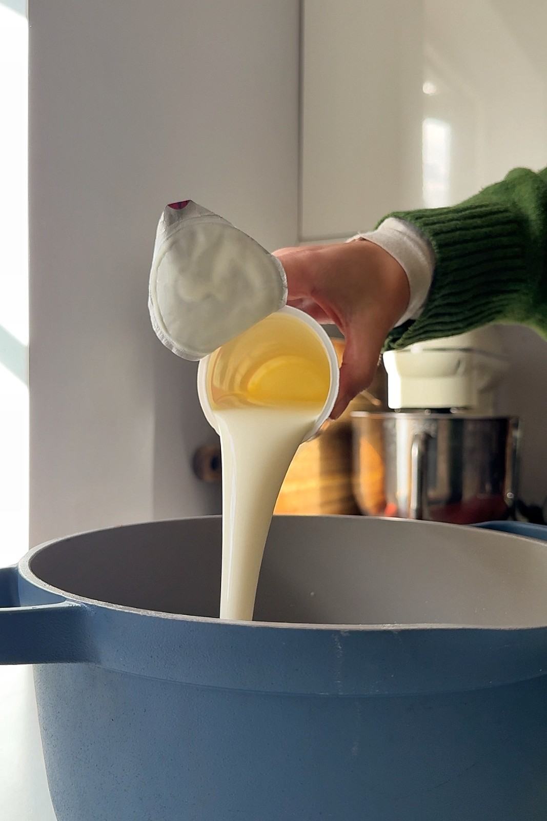Heavy cream being poured into a blue pan to make the peppercorn sauce.
