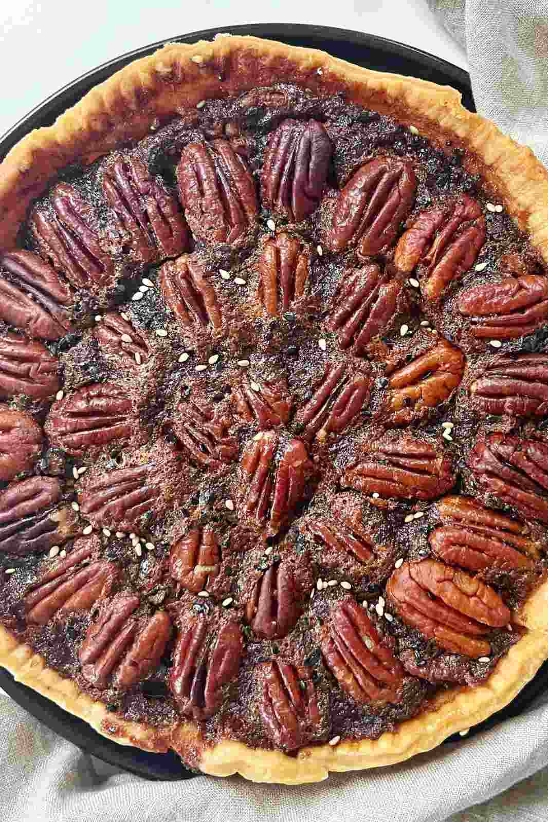 Miso pecan pie on a black plate, showing the top layer of caramelized pecans.