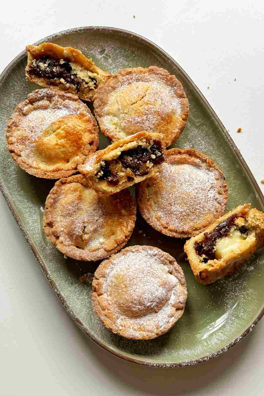 7 homemade mince pies on a green serving platter.