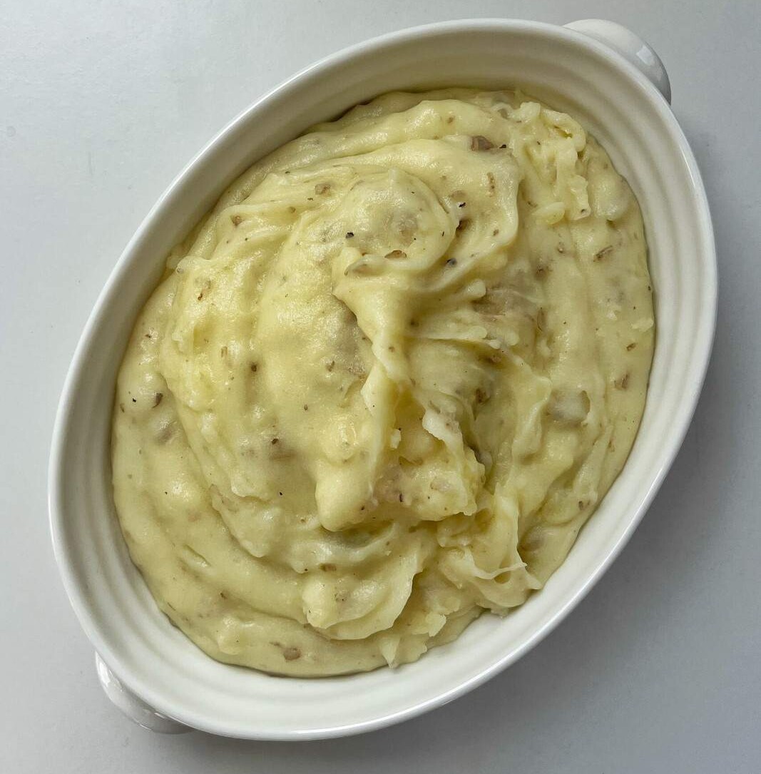 A white bowl full of creamy mashed potato.