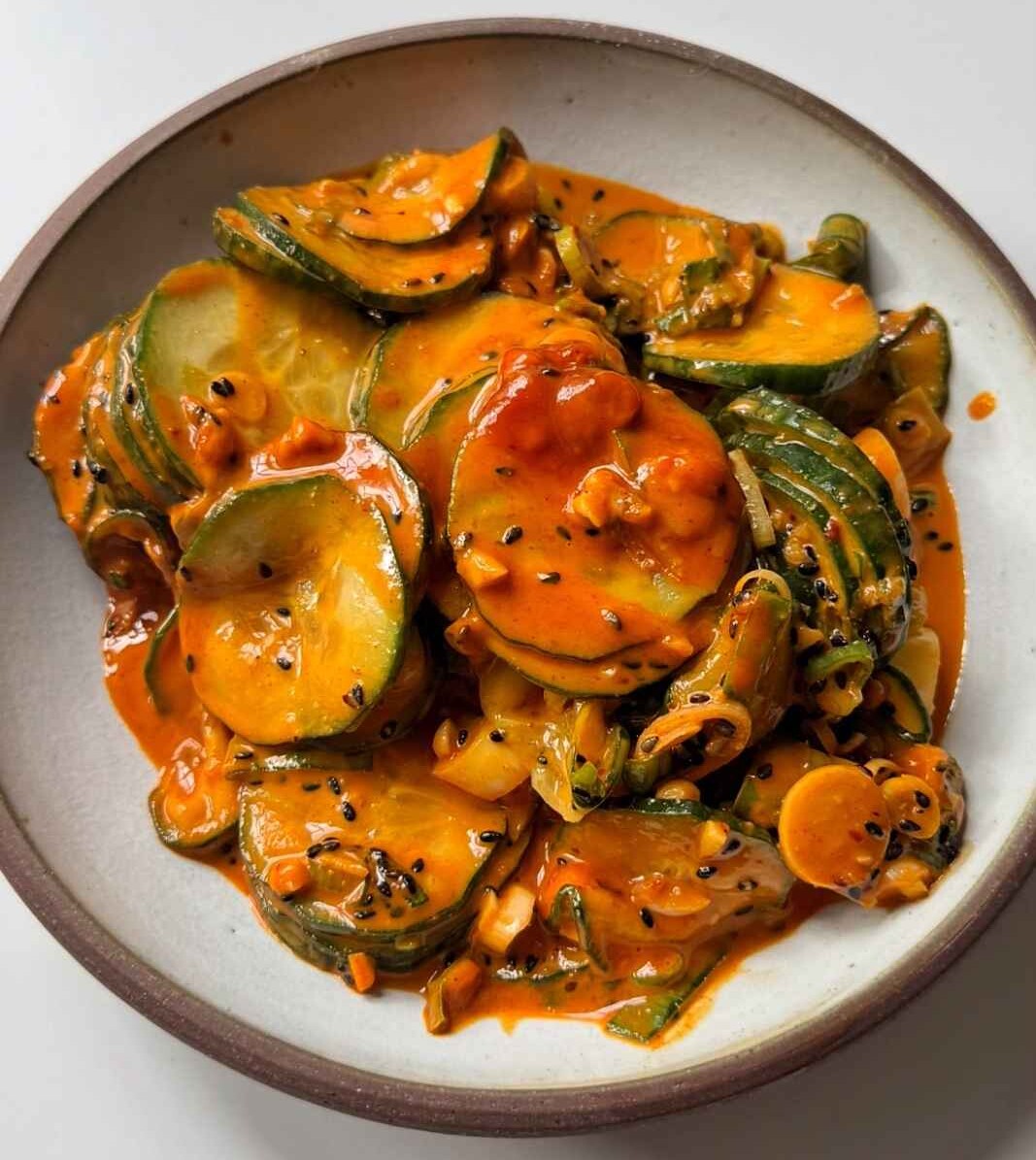 Spicy peanut butter and gochujang cucumber salad in a white bowl.