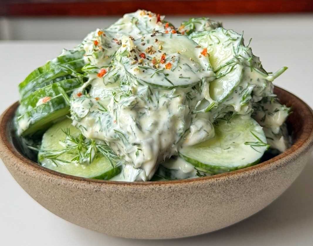 A small grey bowl full of cucumber dill salad.