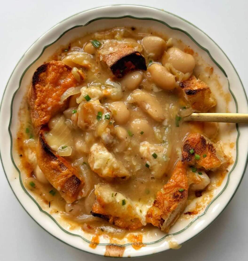 Golden French onion butter bean soup made with caramelised sweet white onions with hints of garlic, thyme, and bay leaves, then topped with baguette and grated cheese.